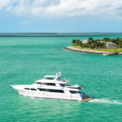 cruise touristic boats or yacht floating by island with houses and green trees on turquoise water and blue cloudy sky, yachting and isle life around beautiful Key West Florida, USA